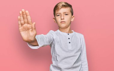 Günlük kıyafetler giyen küçük beyaz çocuk avuç içiyle şarkı söylemeyi kesiyor. Yüzünde olumsuz ve ciddi bir jest olan uyarı ifadesi. 