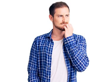 Gündelik kıyafetler giyen yakışıklı beyaz bir adam gergin ve gergin görünüyor. Ağzı tırnak yiyen eller. anksiyete. 