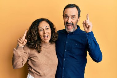 Orta yaşlı İspanyol çift gündelik giysiler giyip şaşkın şaşkın gülüyor, parmaklarıyla işaret ediyor ve kollarını kaldırıyordu.. 