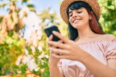 Parkta akıllı telefon kullanarak yaz tarzı giyinen İspanyol bir turist kız..