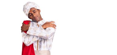 Geleneksel Sherwani elbisesi giyen Afrikalı yakışıklı bir adam mutlu ve pozitif, kendinden emin bir şekilde kendine sarılıyor. Sevgi ve özgüven. 