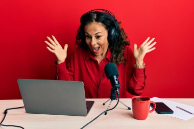 Radyo stüdyosunda çalışan orta yaşlı güzel bir kadın çılgın ve başarıyı kollarını kaldırıp heyecanla haykırarak kutluyor. Kazanan konsept 