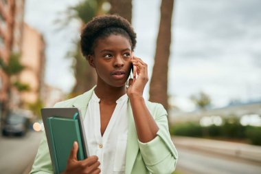 Genç Afro-Amerikan iş kadını ciddi bir ifadeyle şehirdeki akıllı telefondan konuşuyor..