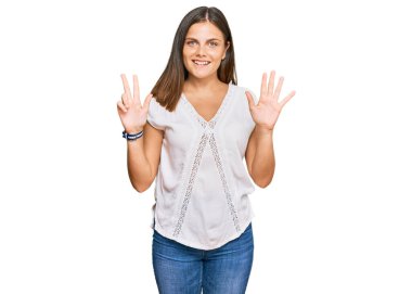 Gündelik giysiler giyen genç beyaz kadın sekiz numarayı gösterip işaret ederken kendinden emin ve mutlu bir şekilde gülümsüyor.. 