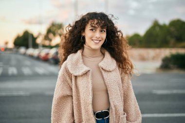 Genç İspanyol kadın gülümseyerek şehirde mutlu mesut dikiliyor.