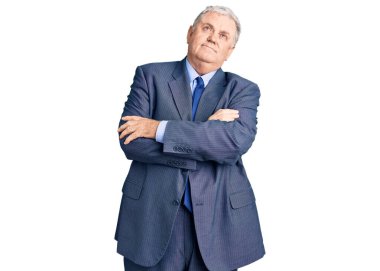 Yaşlı, gri saçlı, iş ceketi giyen, kolları çapraz ve kendinden emin bir şekilde yana bakan adam. 