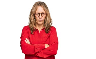 Middle age blonde woman wearing casual shirt over red background skeptic and nervous, disapproving expression on face with crossed arms. negative person.  clipart