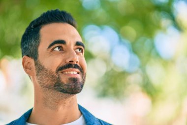 Genç İspanyol adam parkta mutlu bir şekilde gülümsüyor.