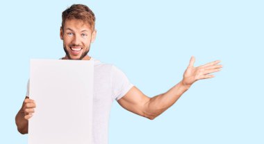 Boş bayrak tutan genç beyaz adam zaferi mutlu bir gülümseme ve ellerini kaldırarak kazanan ifadeyle kutluyor. 