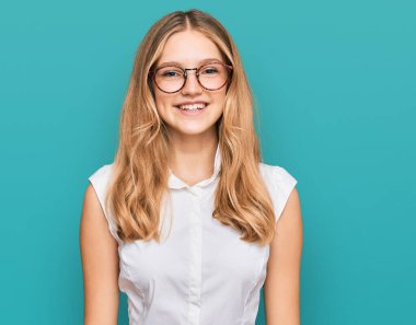 Yüzünde mutlu ve havalı bir gülümseme olan günlük kıyafetler ve gözlük takan güzel beyaz bir kız. şanslı kişi. 