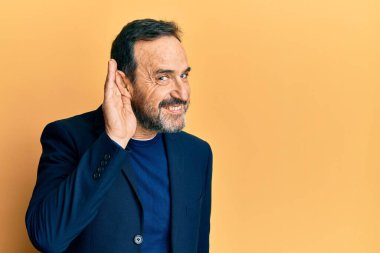 Orta yaşlı İspanyol bir adam iş kıyafetleri giyip sırıtarak kulağına fısıldayarak dedikodu ya da dedikoduları dinliyor. Sağırlık kavramı. 