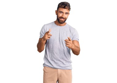 Günlük kıyafetler giyen genç İspanyol adam mutlu ve komik yüzüyle kamerayı işaret ediyor. iyi enerji ve titreşimler. 