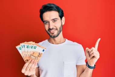 Avro banknotları tutan İspanyol genç adam gülümsüyor. 