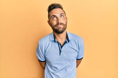 Sakallı, sıradan giyinmiş, gülümseyen, yan tarafa bakıp düşünen yakışıklı bir adam.. 