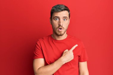 Gündelik kırmızı tişört giyen yakışıklı beyaz adam parmağını yana çevirerek şaşırdı, ağzı açık hayret içinde kaldı.. 