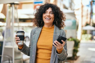 Genç İspanyol iş kadını akıllı telefon kullanıyor. Şehirde kahve içiyor..