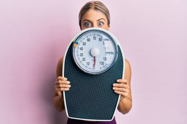 Kilo kaybetmeyi dengelemek için elinde ağırlık tutan güzel sarışın kadın çılgınlığı kutluyor ve başarıyı hayretle haykırıyor.. 