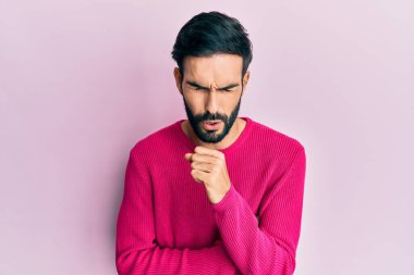 Günlük kıyafetler giyen genç İspanyol adam kendini iyi hissetmiyor ve soğuk algınlığı veya bronşitin belirtisi olarak öksürüyor. sağlık hizmeti kavramı. 