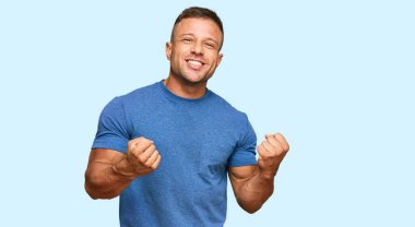 Yakışıklı, sıradan kıyafetler giyen, başarılı olmak için heyecanlanan kolları havada ve gözleri kapalı zaferi kutlayan kaslı adam. Kazanan konsept. 