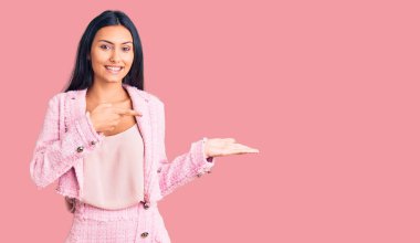 İş kıyafetleri giyen genç ve güzel Latin kız kameraya hayret ediyor ve gülümsüyor.. 