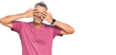 Orta yaşlı, gri saçlı, günlük kıyafetler giyen gözleri kapayan neşeli ve komik gülümseyen bir adam. kör kavram. 