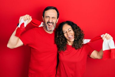 Orta yaşlı bir çift İspanyol kadın ve atkı takan bir adam futbol takımı holiganları tezahürat oyunu komik bir ifadeyle dillerini dışarı çıkarıyorlar.. 