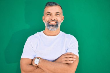 Orta yaşlı, kır saçlı, gülümseyen bir adam şehirde mutlu bir şekilde duruyor..