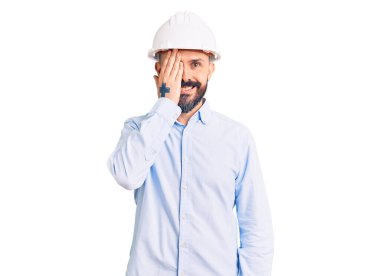Mimar şapkalı genç yakışıklı bir adam bir gözünü eliyle kapatıyor, yüzünde kendine güvenen bir gülümseme ve şaşırtıcı bir duygu var.. 
