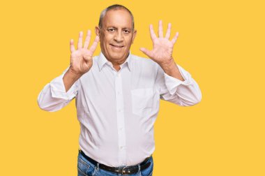 Zarif beyaz gömlek giyen yakışıklı son sınıf öğrencisi dokuz numarayı gösterip işaret ederken kendinden emin ve mutlu bir şekilde gülümsüyor.. 