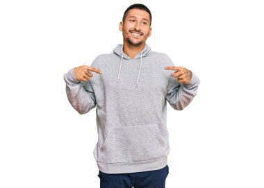 Dövmeli yakışıklı, sıradan bir kazak giyen, kendine güvenen, gülümseyen, kendini gururlu ve mutlu gösteren bir adam.. 