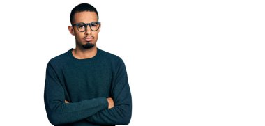 Sıradan kıyafetler giyen, gözlüklü, kuşkucu ve gergin genç Afro-Amerikan erkeği. Yüzünde çapraz kollarla onaylamayan bir ifade var. negatif kişi. 