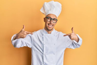 Sakallı, profesyonel aşçı üniforması giyen, kendine güvenen, gülümseyen, kendini gururlu ve mutlu gösteren kel bir adam.. 