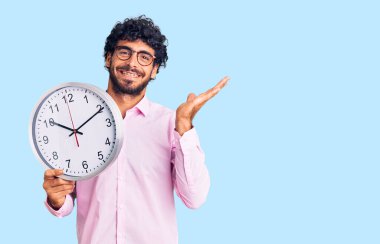 Kıvırcık saçlı ve ayı gibi kocaman saati olan yakışıklı genç adam zaferi mutlu bir gülümsemeyle kutluyor ve ellerini kaldırarak kazanan yüz ifadesi takınıyor. 