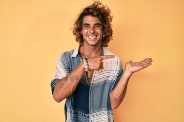 Yaz tarzında giyinen İspanyol genç adam kameraya hayret ediyor ve gülümsüyor.. 