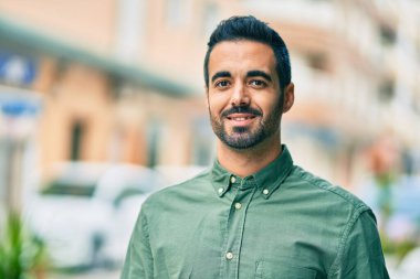 Genç İspanyol adam gülümseyerek şehirde mutlu mesut dikiliyor..