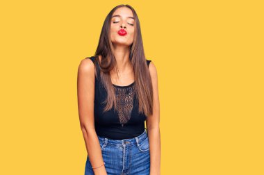 Latin asıllı genç bir kadın, gündelik giysiler içinde kameraya bakıyor ve canlı yayında öpüşüyor. Güzel ve seksi. aşk ifadesi. 