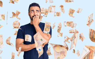 Günlük kıyafetler giyen genç İspanyol adam gergin ve gergin görünüyor. Ağzı tırnak yiyen eller. anksiyete.