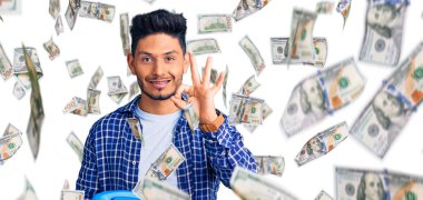 Yakışıklı Latin Amerikalı genç adam elinde antika bir telefon tutuyor parmaklarıyla imza atıyor, gülümsüyor ve mükemmel bir sembol oluşturuyor.