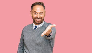 Yakışıklı, orta yaşlı, iş elbiseleri giyen, neşeli gülümseyen, yardım eli uzatan ve kabul gören bir adam.. 