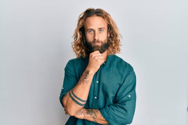 Sakallı, uzun saçlı, sıradan kıyafetler giyen, şüpheyi düşünen, çenesinde parmak olan yakışıklı bir adam. 