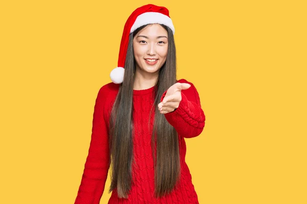 若い中国の女性は挨拶と歓迎として握手を提供する優しい笑顔クリスマスの帽子を身に着けています 成功したビジネス — ストック写真