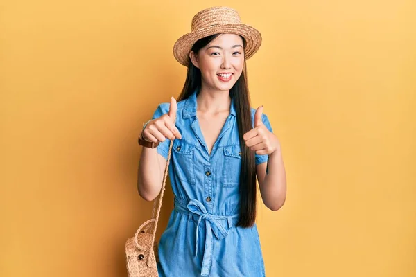 年轻的中国女人戴着夏帽 赞成用手做积极的手势 微笑着竖起大拇指 为成功感到高兴 优胜手势 — 图库照片
