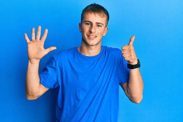 年轻的高加索人穿着休闲的蓝色T恤 手指头指向六号 面带微笑 自信而快乐 — 图库照片