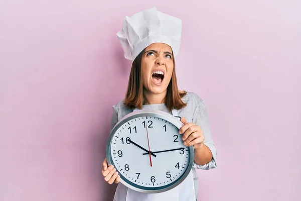 Young Beautiful Woman Wearing Professional Cook Uniform Hat Holding Clock — Zdjęcie stockowe