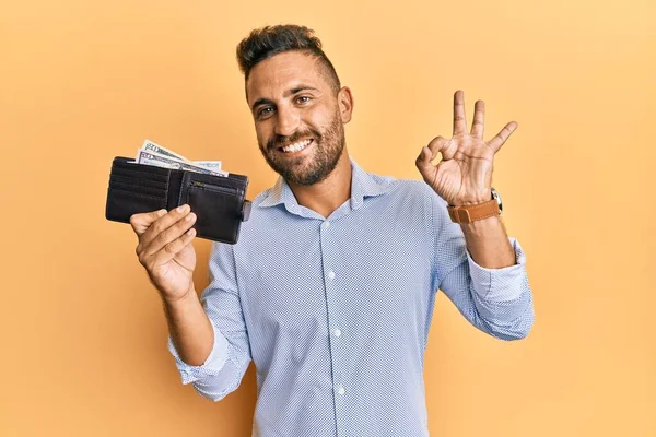 Pohledný Muž Plnovousem Drží Peněženku Dolary Dělá Znamení Prsty Usmívá — Stock fotografie