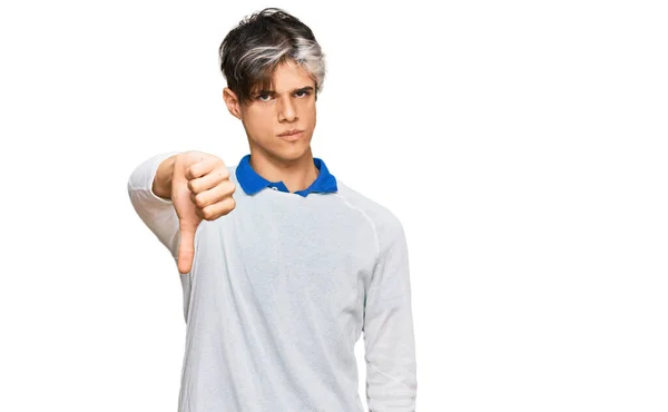 カジュアルな服を着た若いヒスパニック系の男は 親指を下にジェスチャーで拒絶と否定を示す不満と怒りを見ています 悪い表現 — ストック写真