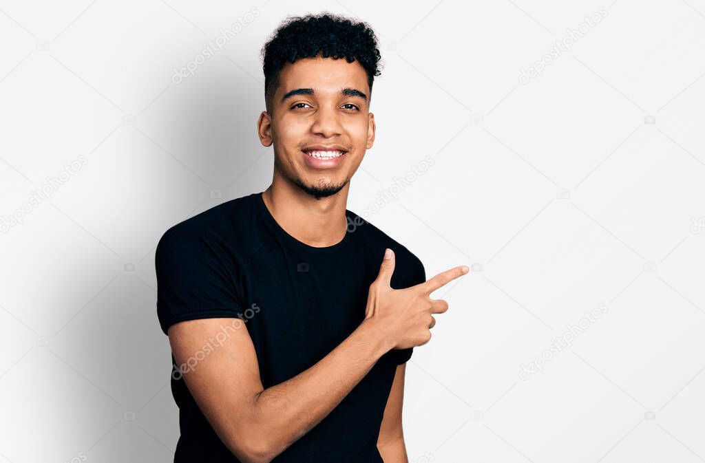 Young african american man wearing casual black t shirt smiling cheerful pointing with hand and finger up to the side 