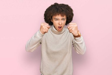 Kışlık yün kazak giyen genç İspanyol kız öfkeyle bağırırken kızgın ve kızgın yumruklar sallıyor. öfke ve agresif konsept. 