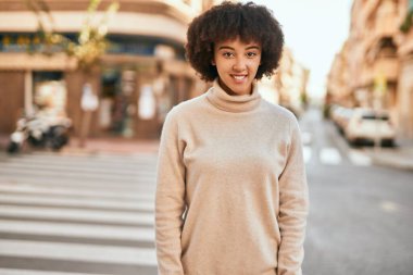 Genç İspanyol kız gülümseyerek şehirde mutlu mesut dikiliyor..