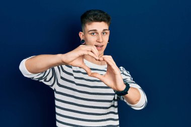 Kulakları genişlemiş, sıradan çizgili tişört giyen, aşkla gülümseyen, elleriyle kalp sembolü yapan beyaz bir çocuk. romantik kavram. 